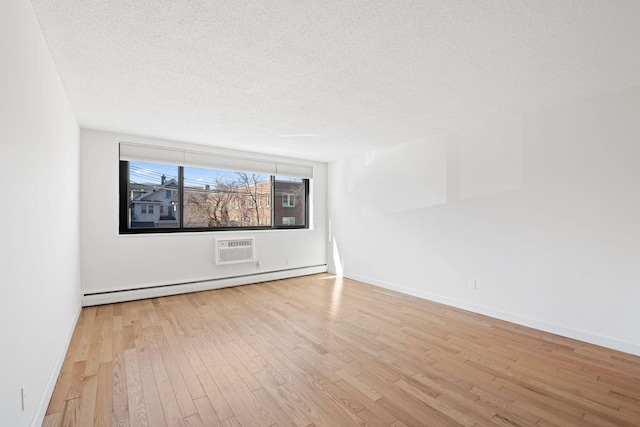 empty room featuring baseboards, a wall unit AC, a baseboard radiator, wood finished floors, and a textured ceiling