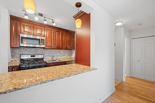 kitchen featuring backsplash, stainless steel microwave, range with gas stovetop, and a sink