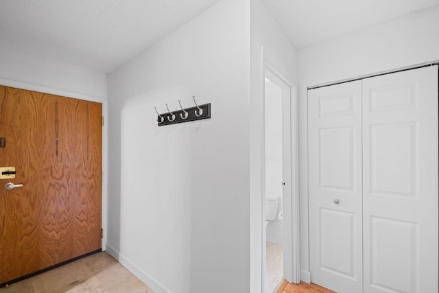 interior space featuring a textured ceiling and baseboards