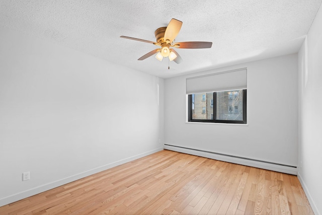 unfurnished room featuring ceiling fan, a textured ceiling, a baseboard heating unit, wood finished floors, and baseboards