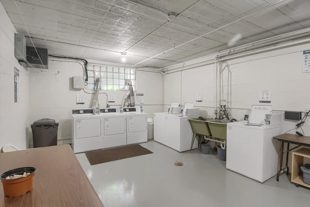 shared laundry area with washer and dryer, a sink, and concrete block wall