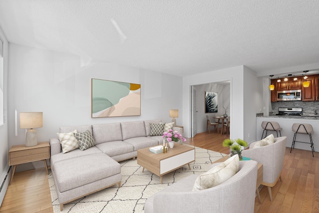 living area with baseboard heating, a textured ceiling, and light wood finished floors