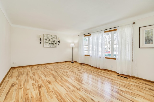 spare room featuring visible vents, baseboards, and wood finished floors