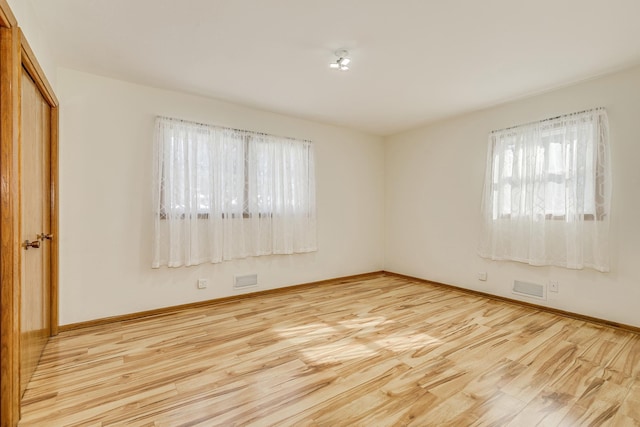 spare room featuring visible vents, baseboards, and wood finished floors