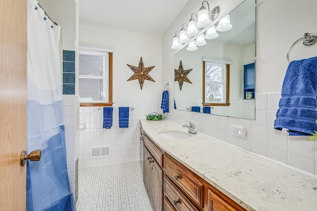 bathroom with tile walls, visible vents, wainscoting, vanity, and tile patterned flooring