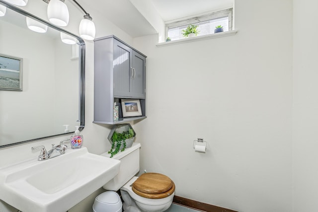 bathroom with a sink, toilet, and baseboards