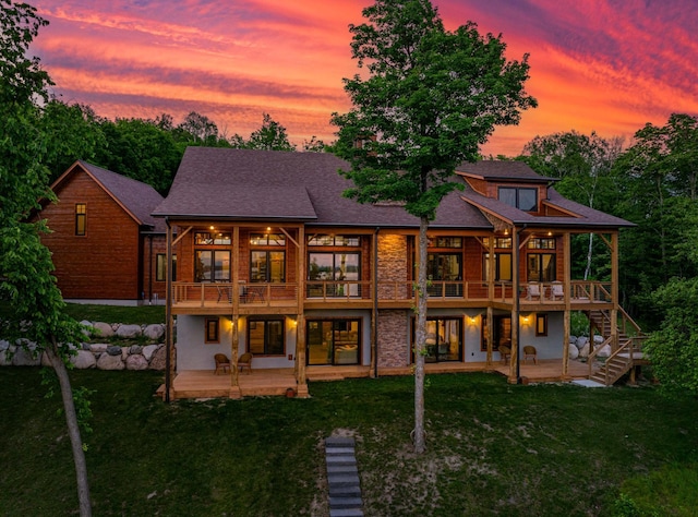 back of property at dusk featuring stairs, a patio, a yard, and a deck