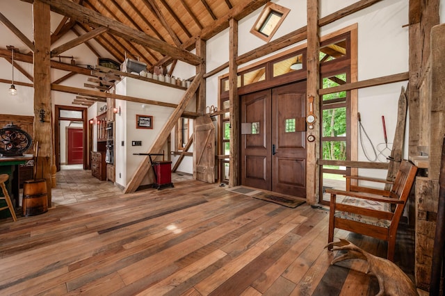 entrance foyer with high vaulted ceiling, wood-type flooring, beamed ceiling, and stairs