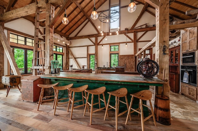 bar featuring wooden ceiling, wood-type flooring, beamed ceiling, multiple ovens, and high vaulted ceiling