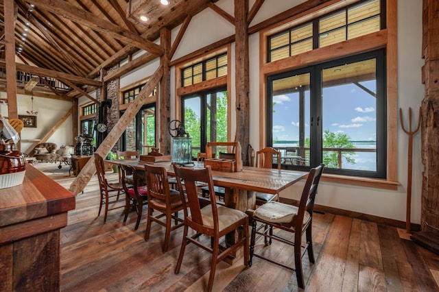 dining room with high vaulted ceiling, wood-type flooring, and plenty of natural light