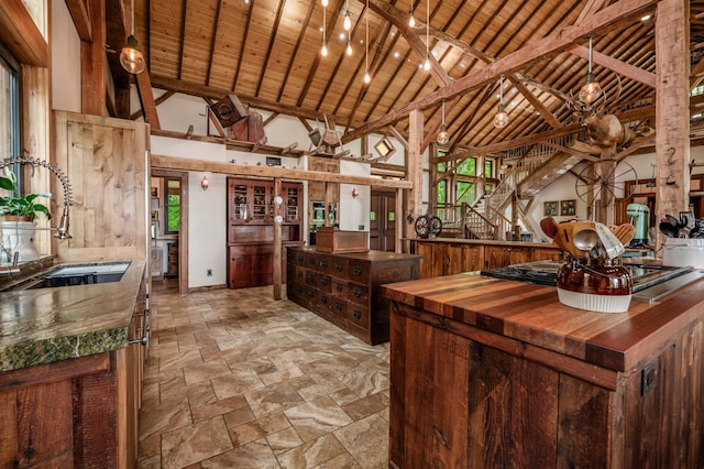 interior space featuring butcher block counters, stone finish floor, a sink, high vaulted ceiling, and wooden ceiling