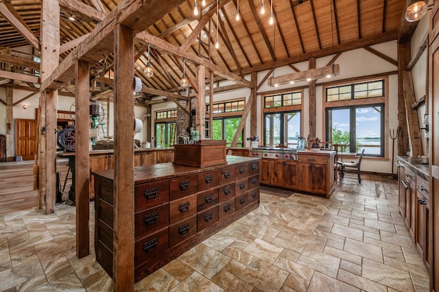 kitchen with high vaulted ceiling, wood ceiling, beamed ceiling, and stone tile floors