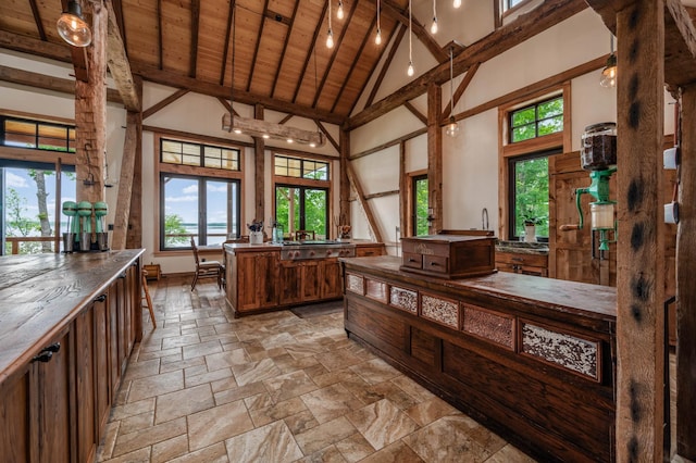 interior space featuring brown cabinets, stone tile flooring, wood ceiling, high vaulted ceiling, and beamed ceiling