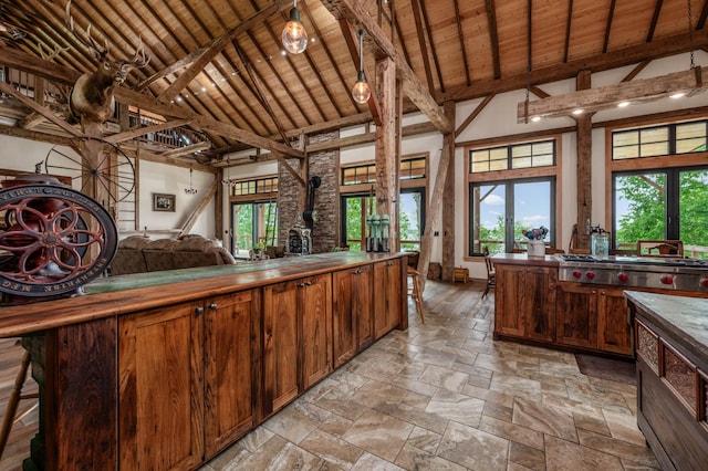 kitchen featuring wooden ceiling, stone tile flooring, stainless steel gas stovetop, high vaulted ceiling, and beam ceiling