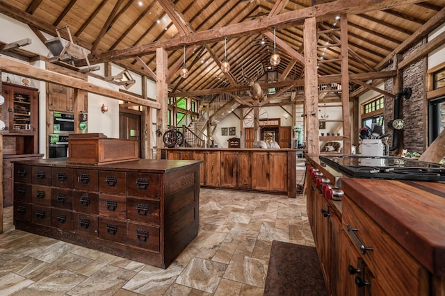 kitchen with high vaulted ceiling, butcher block countertops, wood ceiling, a center island, and stone tile flooring