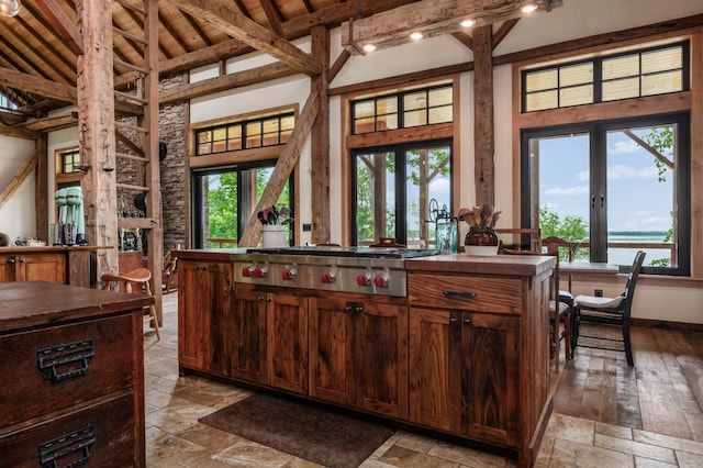 kitchen featuring stone tile floors, stainless steel gas cooktop, beamed ceiling, french doors, and high vaulted ceiling