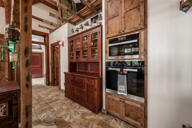 kitchen featuring glass insert cabinets, stainless steel double oven, and stone finish flooring