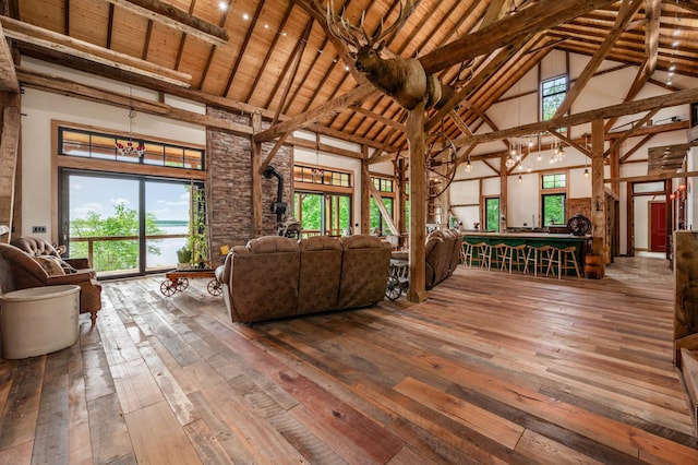 unfurnished living room with a wood stove, wood-type flooring, and high vaulted ceiling