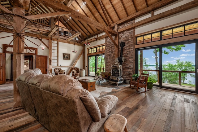 living area with beam ceiling, wood ceiling, a wood stove, high vaulted ceiling, and hardwood / wood-style floors