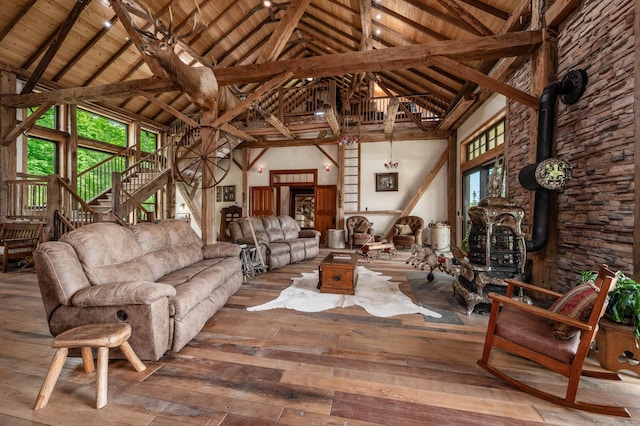 living room featuring high vaulted ceiling, wooden ceiling, hardwood / wood-style flooring, beam ceiling, and a wood stove