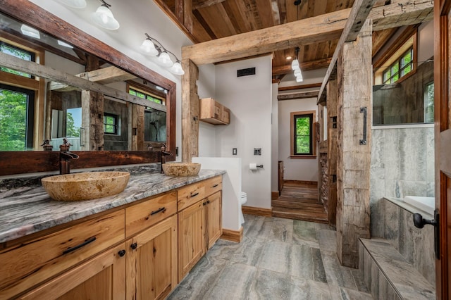 full bathroom featuring a sink, beamed ceiling, toilet, and double vanity