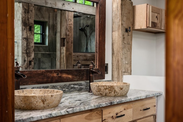 full bathroom with double vanity, walk in shower, and a sink