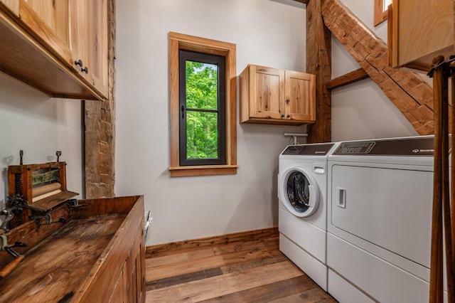 laundry room with separate washer and dryer, hardwood / wood-style flooring, and cabinet space