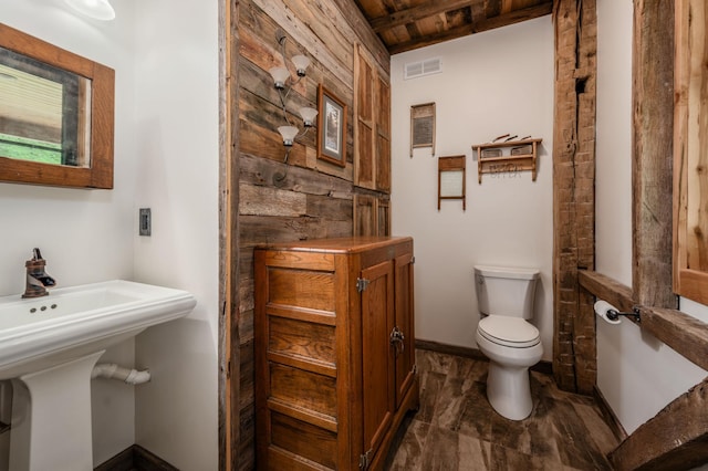 bathroom featuring visible vents, toilet, wood ceiling, a sink, and baseboards