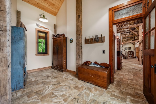 entryway with high vaulted ceiling, wooden ceiling, baseboards, stairway, and stone finish flooring