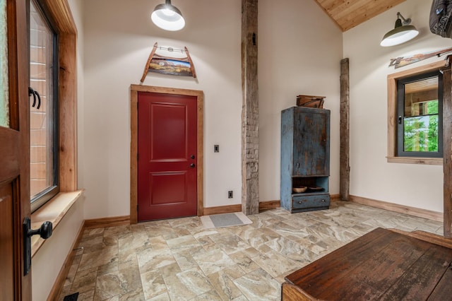 entryway featuring lofted ceiling, stone finish flooring, and baseboards