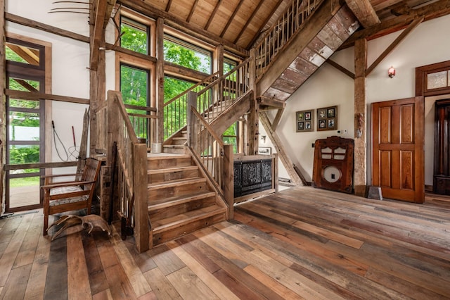 stairs featuring high vaulted ceiling, a wealth of natural light, and hardwood / wood-style flooring