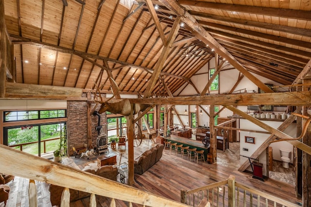 unfurnished living room with high vaulted ceiling, beam ceiling, wood-type flooring, and wood ceiling