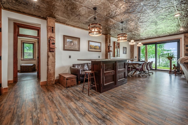 bar with dark wood-type flooring, baseboards, hanging light fixtures, a dry bar, and an ornate ceiling