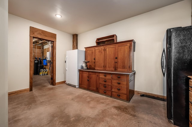 kitchen featuring brown cabinetry, freestanding refrigerator, and concrete floors