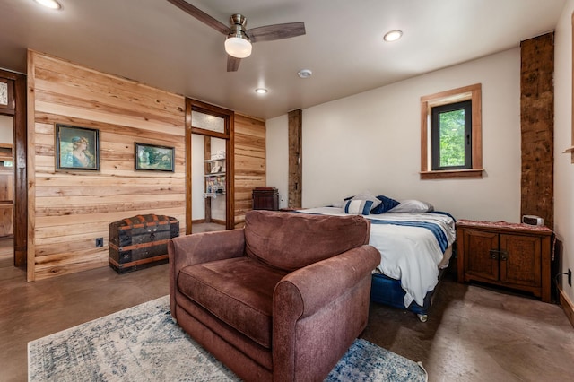 bedroom featuring finished concrete floors, recessed lighting, ceiling fan, and wooden walls