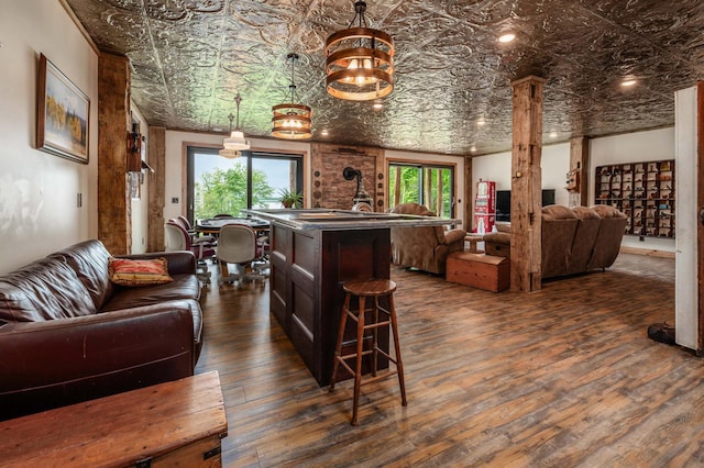 living area with dark wood-style flooring, an ornate ceiling, and ornate columns