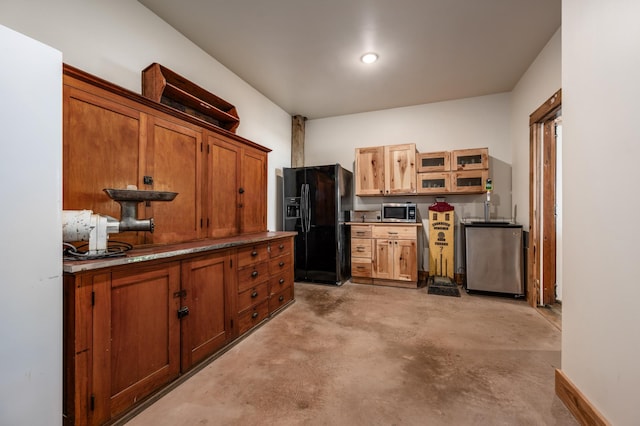 kitchen featuring brown cabinetry, glass insert cabinets, stainless steel appliances, and concrete flooring