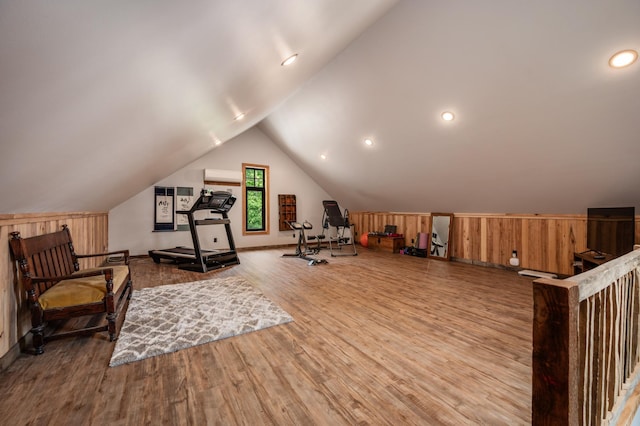 workout area featuring wood walls, vaulted ceiling, wood finished floors, and an AC wall unit