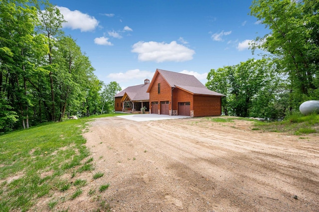 exterior space featuring a garage, driveway, and a chimney