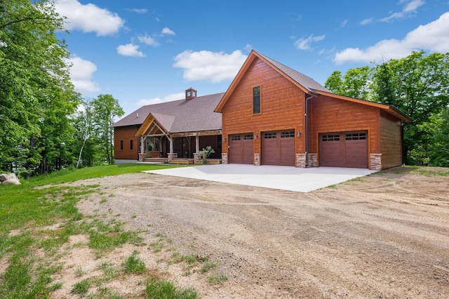 view of front of house featuring a garage, stone siding, and driveway