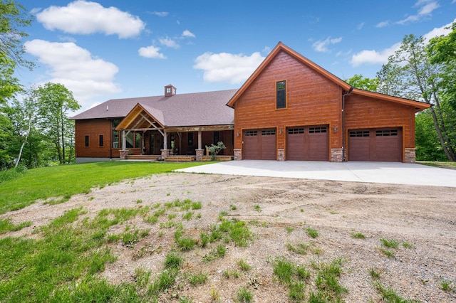 view of front of home featuring covered porch, a garage, concrete driveway, stone siding, and a front lawn