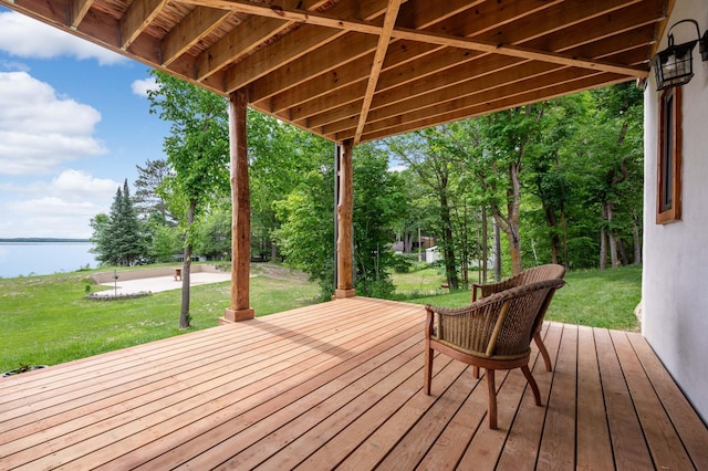 wooden deck with a water view and a lawn