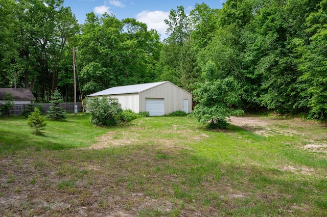 view of yard featuring a garage, fence, and an outbuilding