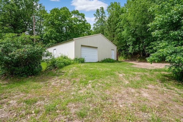 view of yard with a garage, driveway, and an outdoor structure