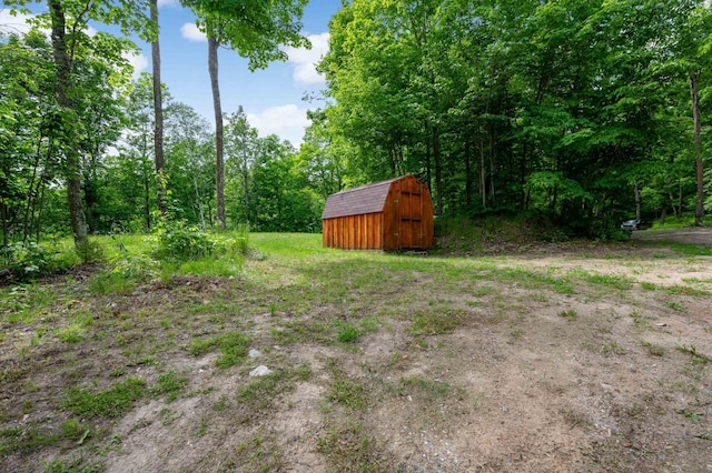 view of yard with an outbuilding, a view of trees, and a shed