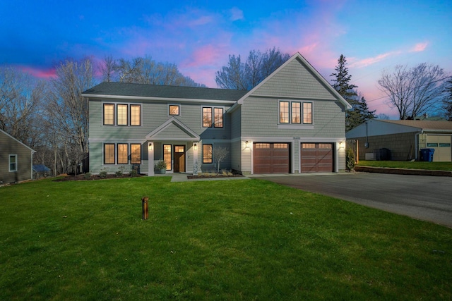 view of front of home with aphalt driveway, a front lawn, and an attached garage