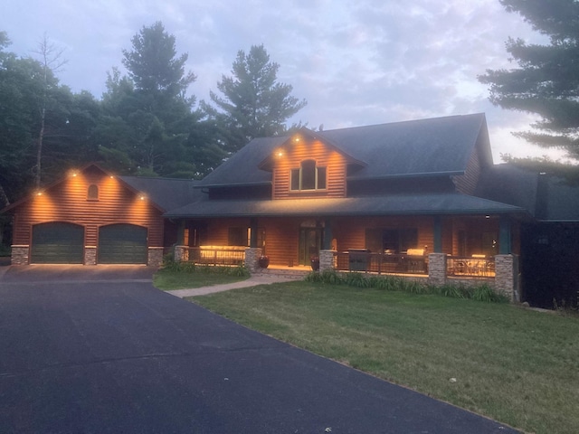 view of front of home featuring covered porch, an attached garage, concrete driveway, and a front yard