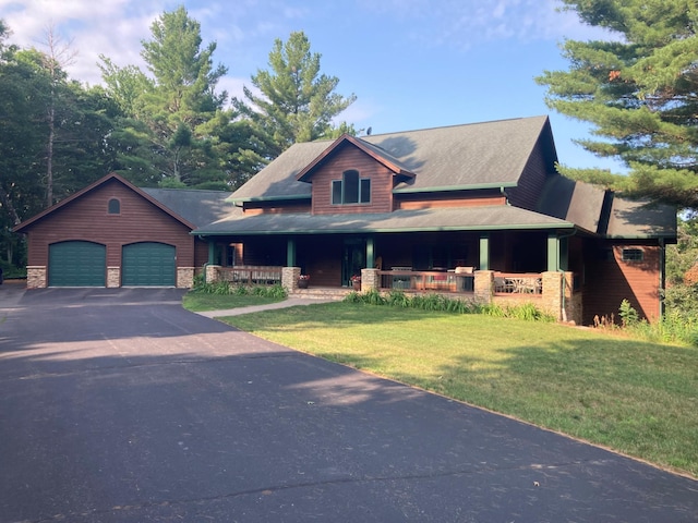 view of front of home with a porch, a front yard, stone siding, and a detached garage