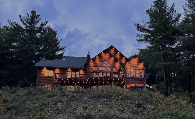 rear view of property featuring a wooden deck, a chimney, and log veneer siding