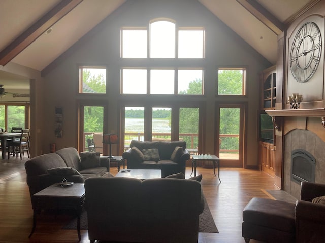 living area featuring a fireplace, high vaulted ceiling, wood finished floors, and beamed ceiling